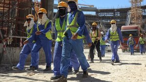 Ausländische Bauarbeiter gehen über die Baustelle eines WM-Stadions in Doha. Foto: dpa