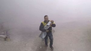 Dieses vom Syrischen Zivilschutz (Weißhelme) bereitgestellte Foto zeigt einen Notarzt, der seinen verletzten Sohn nach einem Luftangriff auf einen von Rebellen kontrollierten Vorort von Damaskus wegbringt. Foto: Syrian Civil Defense White Helme
