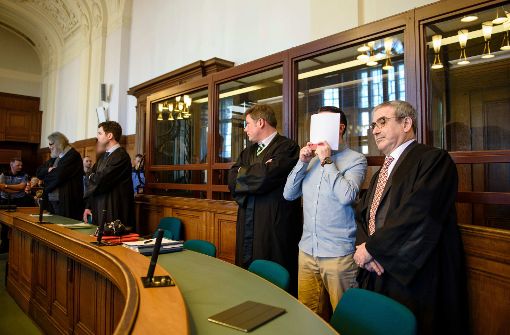 Die Angeklagten Hamdi H. (zweiter von rechts) und Marvin N. (fünfter von rechts, halb verdeckt) stehen am 27. Februar 2017 in Berlin in einem Gerichtssaal des Landgerichtes Berlin zwischen ihren Anwälten, Hamdi H. hält sich eine Akte vor das Gesicht. Foto: dpa