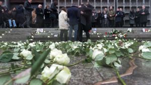 Angehörige legen bei der Einweihung der Gedenkstätte mit einem aus Bronze nachempfundenen Riss im Boden an der Gedächtniskirche auf dem Breitscheidplatz in Berlin Kerzen nieder und umarmen einander. Foto: dpa