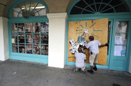 Arbeiter vernageln die Scheiben eines Geschäfts mit Brettern in Vorbereitung auf den Sturm „Marco“. Foto: dpa/Gerald Herbert
