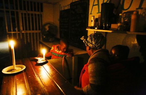 Eine Frau in Kapstadt beleuchtet ihre Restaurantküche mit Kerzenlicht. Die Stromknappheit setzt den Menschen in ihrem Alltag zu und zwingt zum Aufgeben. Foto: dpa/Nic Bothma