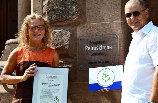 Martina und Dietmar Tietke mit dem „Grünen Gockel“. Ende Juli wurde die evangelische Petruskirchengemeinde mit dem Ökosiegel ausgezeichnet. Foto: Fatma Tetik