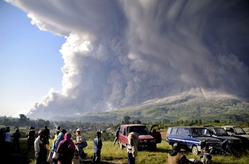 Menschen beobachten eine Eruption des Vulkans Sinabung. Der knapp 2500 Meter hohe Vulkan ist einer von mehr als 120 aktiven Vulkanen in Indonesien. Foto: Uncredited/AP/dpa