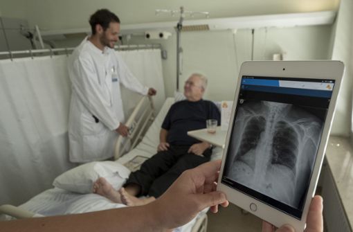 Oberarzt Michael Svoboda bei einem seiner Patienten. Röntgenbilder  kann er nun  direkt am Bett  auf dem Tablet zeigen. Foto: factum/Weise
