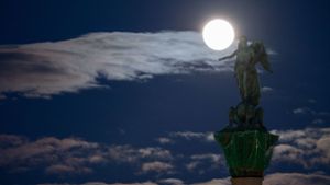 Der Mond leuchtet hinter der Statue der römischen Göttin Concordia, die auf der Jubiläumssäule über dem Stuttgarter Schlossplatz thront. Foto: dpa