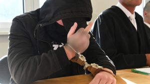 Der 19-jährige Angeklagte streckt zu Prozessbeginn auf der Anklagebank sitzend den Mittelfinger zu den auf ihn gerichteten Kameras Foto: dpa
