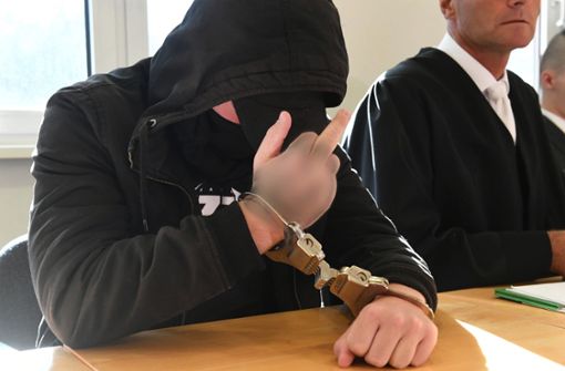 Der 19-jährige Angeklagte streckt zu Prozessbeginn auf der Anklagebank sitzend den Mittelfinger zu den auf ihn gerichteten Kameras Foto: dpa