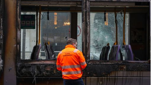 Ein Mann steht vor einer ausgebrannten Stadtbahn. Foto: AFP/PAUL FAITH