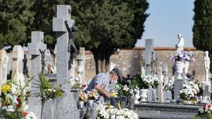 In Spanien legt ein älterer Mann an Allerheiligen Blumen auf ein Grab. Foto: dpa/Europa Press