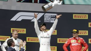 So feiert  ein Sieger: Mercedes-Pilot Lewis Hamilton  wirft die Trophäe in die Luft. Foto: dpa
