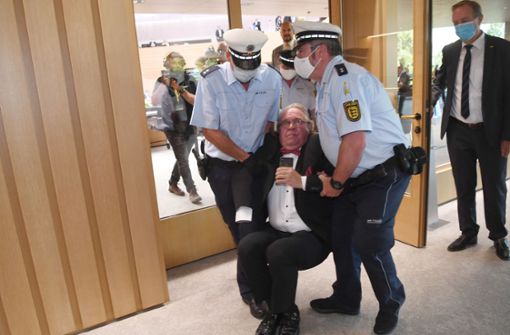 Der Abgeordnete Heinrich Fiechtner wird von zwei Polizisten hinaus getragen. Foto: dpa/Marijan Murat