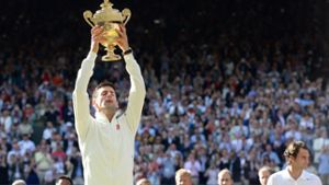 Novak Djokovic reckt in Wimbledon die Trophäe in die Luft. Foto: dpa