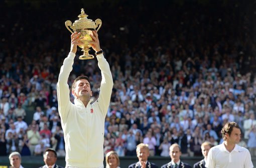 Novak Djokovic reckt in Wimbledon die Trophäe in die Luft. Foto: dpa