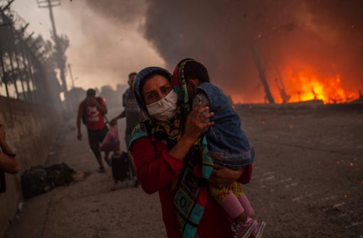 Ihre Kinder auf dem Arm versuchen die Flüchtlinge von Moria, den Flammen zu entkommen. Foto: AFP/ANGELOS TZORTZINIS