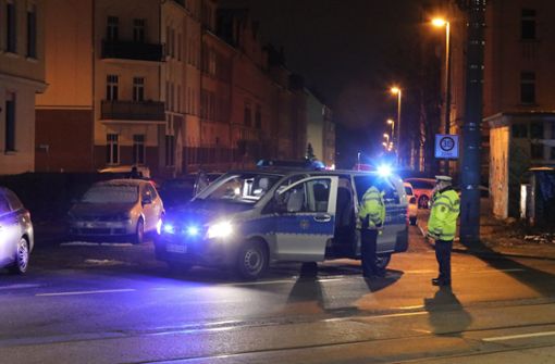 Polizisten stehen an einer durch ein Polizeifahrzeug blockierten Straße. Das Landeskriminalamt Sachsen hat am Mittwochmorgen eine groß angelegte Razzia in Dresden und Leipzig gestartet Foto: dpa