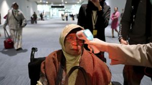 Ein Gesundheitsbeamter scannt die Körpertemperatur einer Passagierin bei ihrer Ankunft am Soekarno-Hatta International Airport im indonesischen Tangerang. Foto: dpa