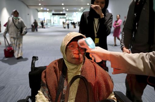 Ein Gesundheitsbeamter scannt die Körpertemperatur einer Passagierin bei ihrer Ankunft am Soekarno-Hatta International Airport im indonesischen Tangerang. Foto: dpa