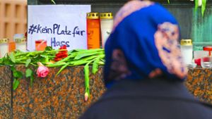 Eine Frau steht in Hanau vor dem Brüder-Grimm-Denkmal, an dem Blumen, Kerzen und eine Botschaft niedergelegt worden sind. Foto: dpa