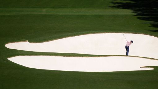 Spannung in der Ferne: Der Golfspieler Rory McIlroy aus Nordirland schlägt am achten Loch. Seit 1934 findet das Golfturnier US Masters auf demselben Golfplatz in Georgia, USA statt. Foto: Charlie Riedel/AP/dpa