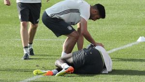Emre Can beugt sich über den verletzten Antonio Rüdiger während des öffentlichen Trainings der deutschen Fußballnationalmannschaft. Foto: dpa