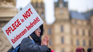 Bei einer Protestaktion vor dem Schweriner Landtag hält eine Teilnehmerin ein Schild mit der Aufschrift Pflege in Not - Existenzen bedroht!. Foto: Jens Büttner/dpa