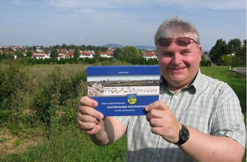 Markus Munk mit seinem neuen Postkartenbuch vor der Silhouette Schmidens Foto: Eva Schäfer