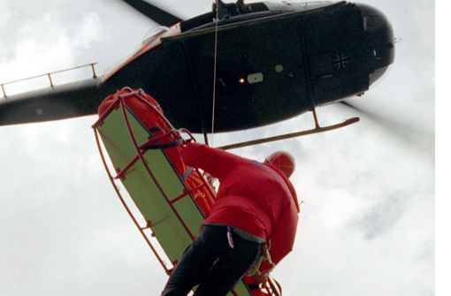 Ein Retter der Bergwacht, an einer Seilwinde eines Bundeswehr-Rettungshubschraubers hängend, seilt sich im Hochgebirge des Zugspitzmassivs mit einer Rettungstrage ab (Archivbild). Foto: dpa/