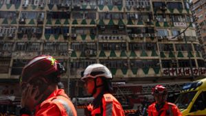 Im Hintergrund ist das ausgebrannte Hochhaus in Hongkong zu sehen - bei der Feuerwehr waren zahlreiche Hilferufe eingegangen. Foto: Louise Delmotte/AP