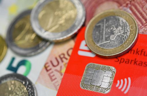 Eine EC-Karte mit integrierter NFC-Technik zum bargeldlosen Bezahlen liegt zusammen mit Euro-Münzen und -Banknoten auf einem Tisch. Foto: dpa