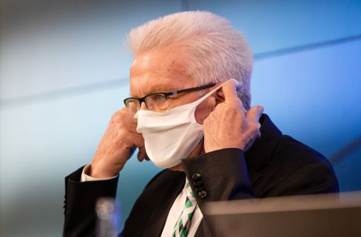 Winfried Kretschmann nimmt zu Beginn der Regierungspressekonferenz seine Nase-Mund-Schutzmaske ab. Foto: picture alliance/dpa/Christoph Schmidt