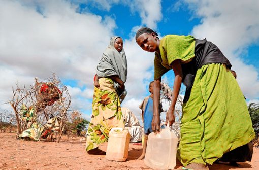 Somalische Frauen tragen  ihre tägliche Ration an Trinkwasser zu ihren Zelten im Flüchtlingslager in Dadaab (Kenia). Foto: dpa/Boris Roessler